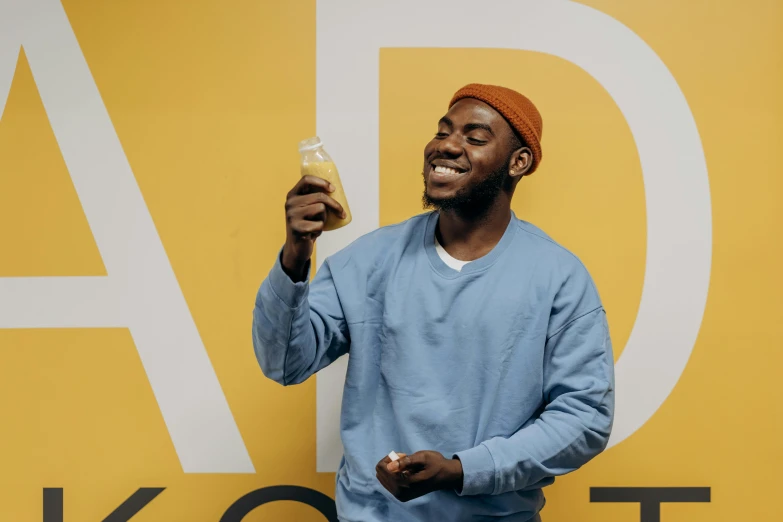 a man standing in front of a sign holding a drink, pexels contest winner, academic art, wearing a yellow hoodie, kano), laughing, ice cream on the side