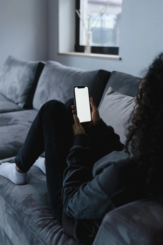 a woman sitting on a couch using a cell phone, trending on pexels, dark grey skin, dark. no text, watching tv, 6 : 3 0 am