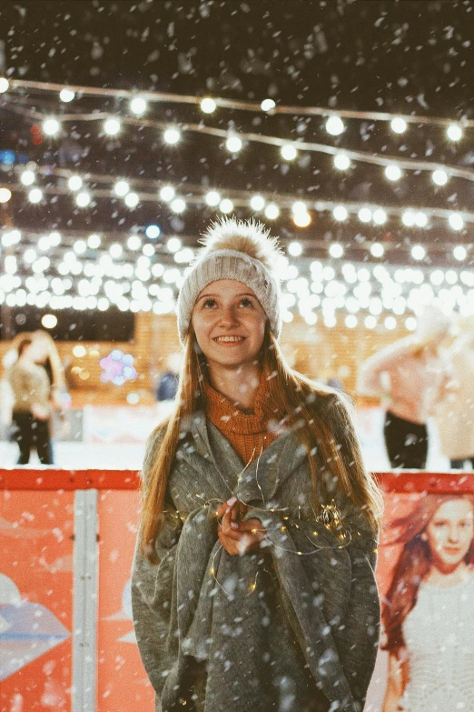 a woman is standing outside in the snow, lots of lights, standing in an arena, instagram post, festive