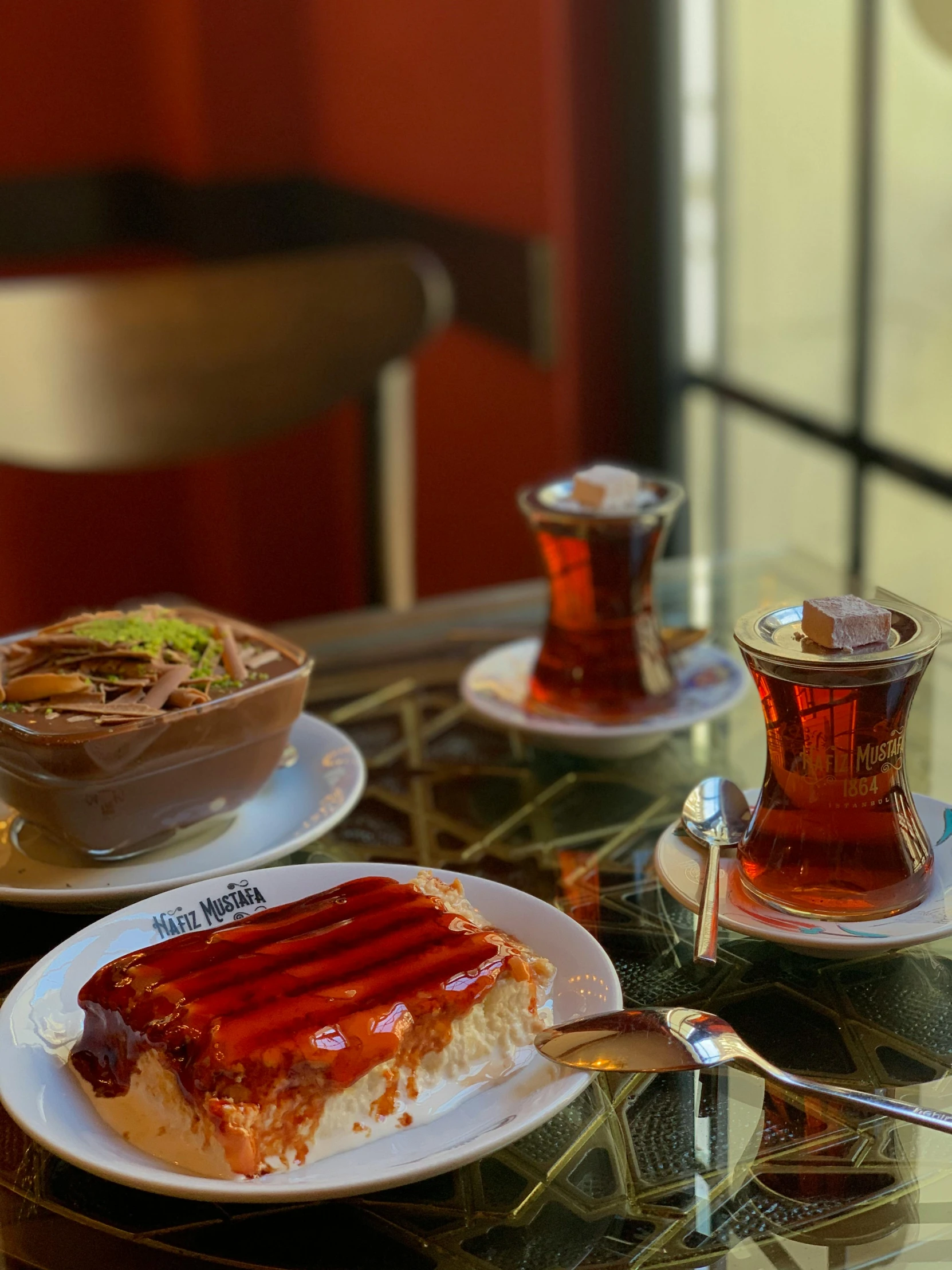 a glass table topped with plates of food, dau-al-set, caramel, baris yesilbas, profile image, tea