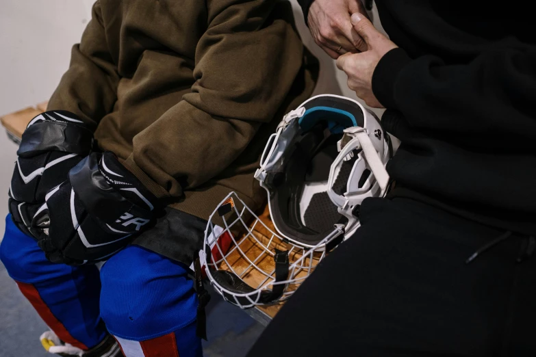 a couple of people sitting next to each other on a bench, by Adam Marczyński, pexels contest winner, full ice hockey goalie gear, helmet view, thumbnail, bottom angle