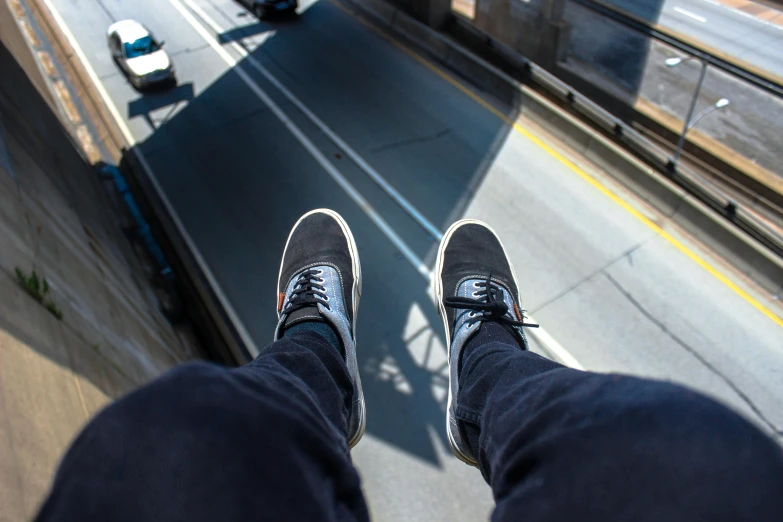 a person standing on a ledge with their feet in the air, pexels contest winner, photorealism, worm's - eye view, car jump, sitting down casually, skybridges