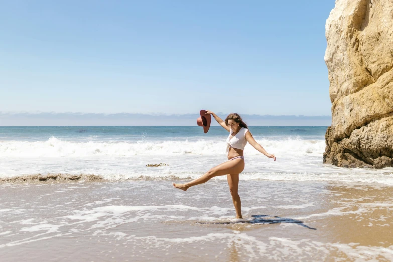 a woman standing on top of a beach next to the ocean, arabesque, malibu canyon, kick flip, profile image, brown