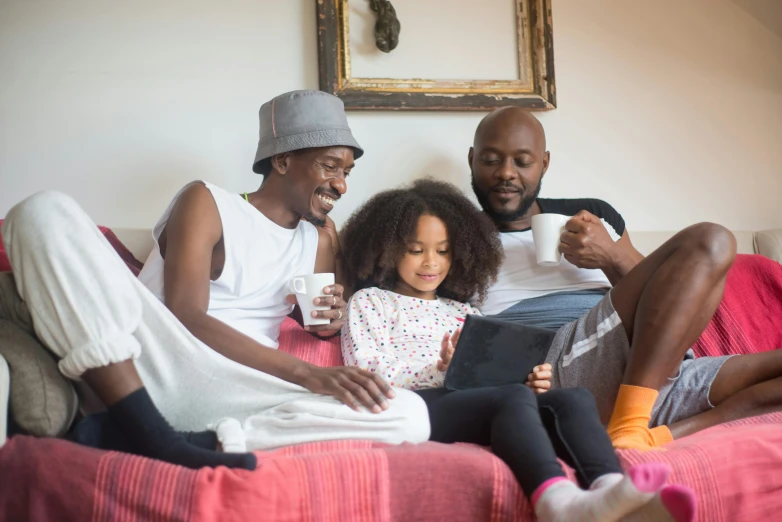 a family sitting on a couch looking at a laptop, pexels, black arts movement, avatar image, someone in home sits in bed, fatherly, using a magical tablet