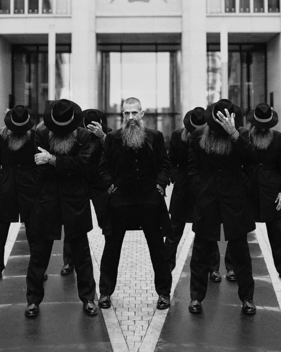 a group of men standing in front of a building, inspired by John Brown Abercromby, unsplash, surrealism, long beard, in black uniform, wearing a plug suit, ffffound