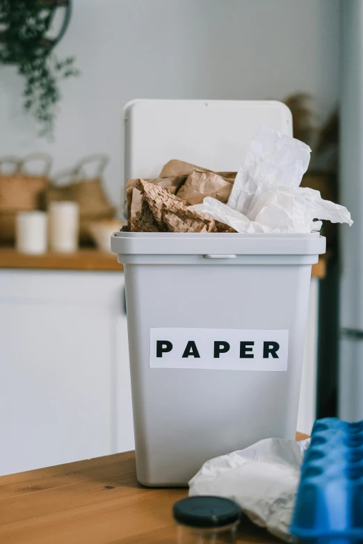 a white trash can sitting on top of a wooden table, pexels contest winner, product label, paper decoration, in a kitchen, sustainable