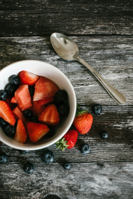 a bowl of strawberries and blueberries on a wooden table, pexels contest winner, renaissance, spoon placed, cutlery, infinite, looks smart