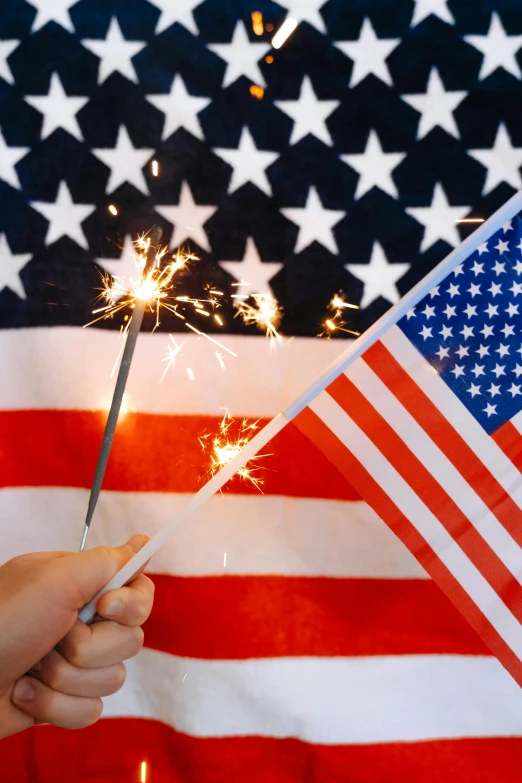 a person holding a sparkler in front of an american flag, slide show, decorations, flags, deity)