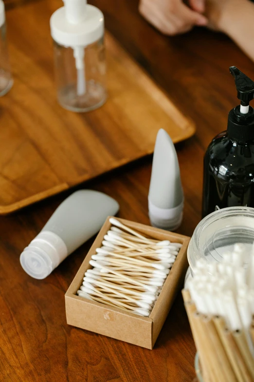 a person sitting at a table with toothbrushes and toothpaste, natural materials, square, bottles, up close