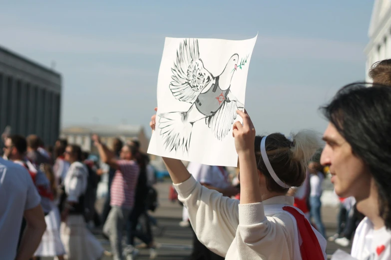 a person holding up a drawing in front of a crowd, a cartoon, by Francesco Furini, pexels contest winner, graffiti, white dove, parade, environmental shot, catholic