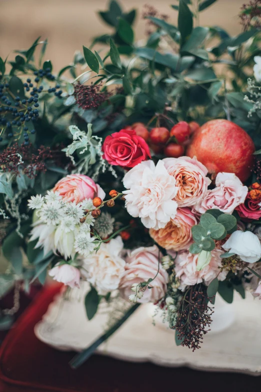 a bouquet of flowers sitting on top of a table, by Elsie Few, trending on unsplash, baroque, made of flowers and berries, lush chic garden, low detail, peach embellishment