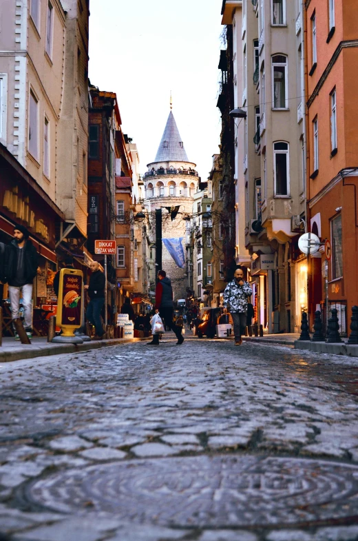 a cobblestone street with a clock tower in the background, inspired by Niyazi Selimoglu, pexels contest winner, ottoman sultan, domes, in the center of the image, belle epoque