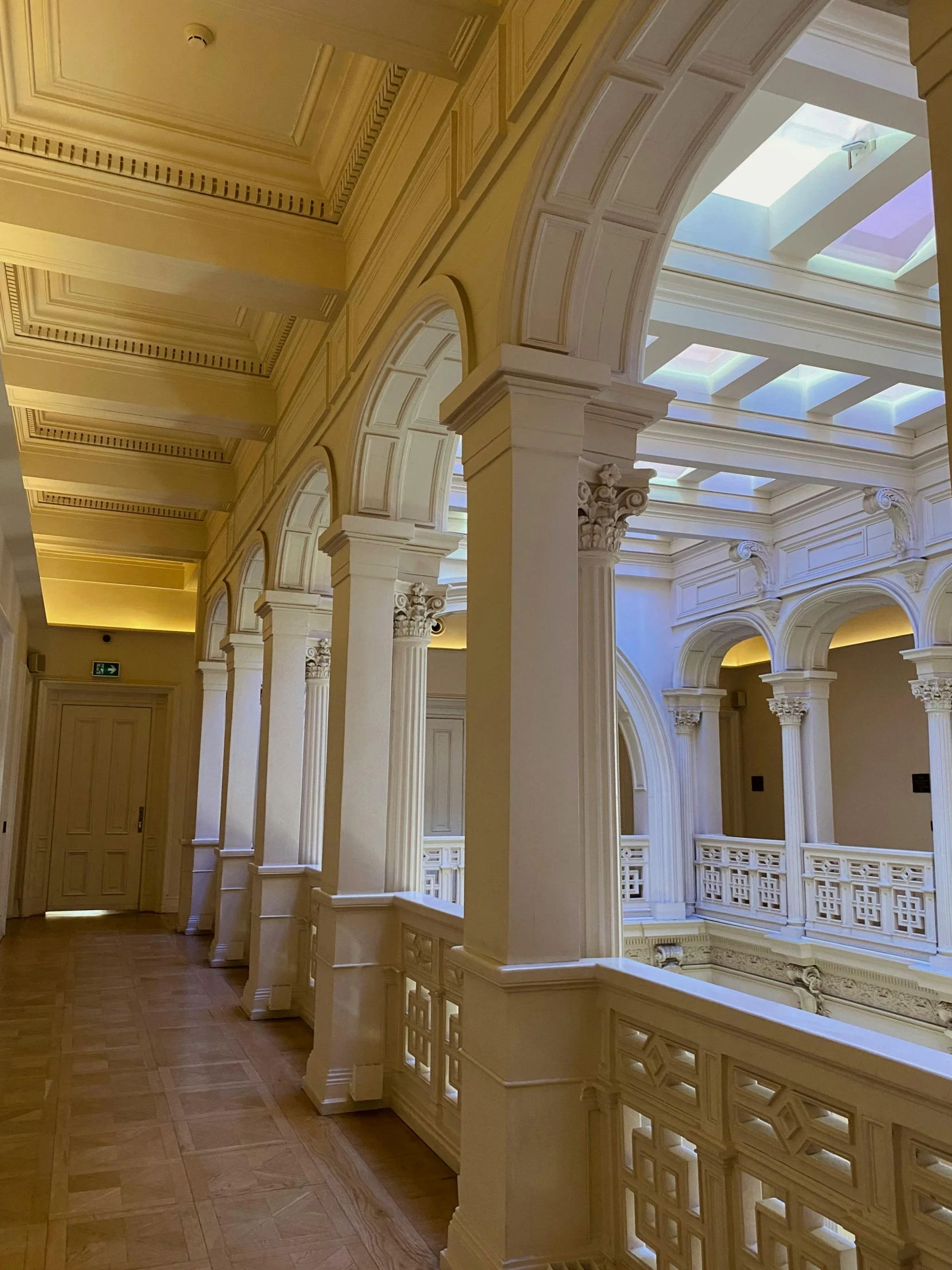 a long hallway with columns and a skylight, inspired by Sydney Prior Hall, unsplash, light and space, in balcony of palace, soft lighting from above, snapchat photo, yellow lighting from right