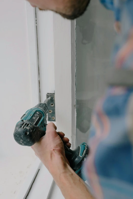 a man using a drill to fix a window, pexels contest winner, hand on the doorknob, low quality photo, color footage, profile image