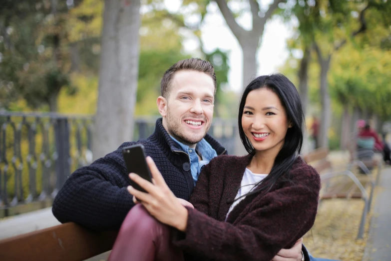 a man and a woman are sitting on a bench, a picture, taking a selfie, half asian, australian, full frame image