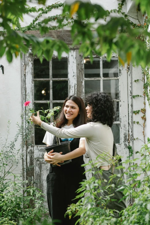 a couple of women standing next to each other, pexels contest winner, renaissance, in a garden of a house, hispanic, picking up a flower, promotional image