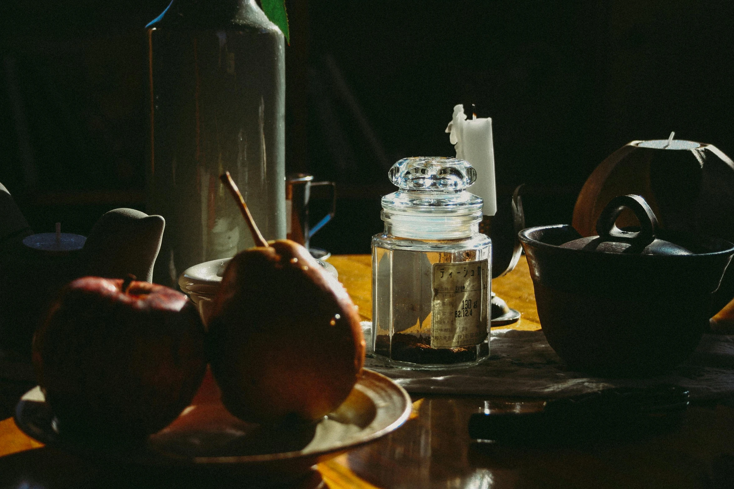 a wooden table topped with a plate of fruit, a still life, by Daniel Lieske, pexels contest winner, process art, glowing jar, lo-fi, autumn, inside a glass jar