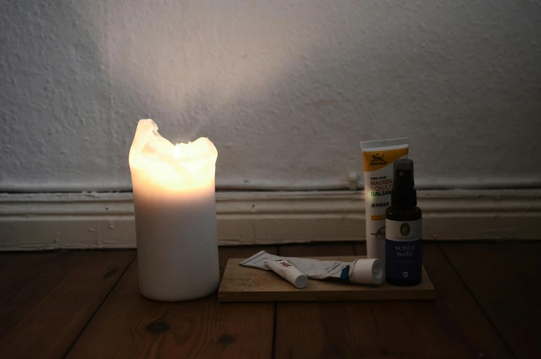 a white candle sitting on top of a wooden table, healing tubes, soft coloured gel lighting, battered, elliot alderson