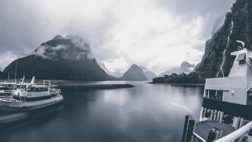 a boat in a body of water with mountains in the background, shades of grey, lachlan bailey, top selection on unsplash, te pae