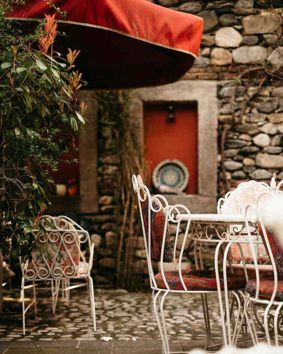 a patio with a table and chairs and an umbrella, by Elsa Bleda, pexels contest winner, art nouveau, rustic setting, thumbnail, multiple stories, white and red color scheme