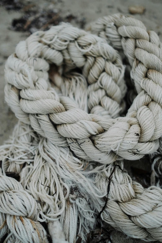 a pile of rope sitting on top of a sandy beach, unsplash, process art, silver，ivory, textile, islamic, made of wool