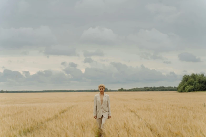 a man standing in a field of wheat, an album cover, by Emma Andijewska, tan suit, androgynous person, ignant, full body image