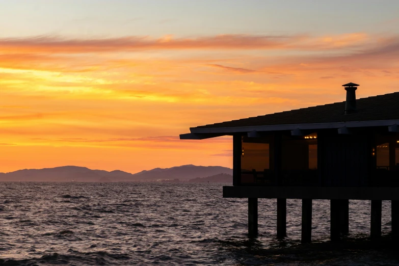 a house sitting on top of a pier next to the ocean, unsplash, modernism, sunset kanagawa prefecture, cannes, brown, beach bar