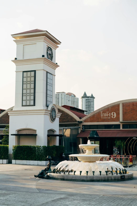 a building with a fountain in front of it, bangkok townsquare, shuttered mall store, clock tower, at home