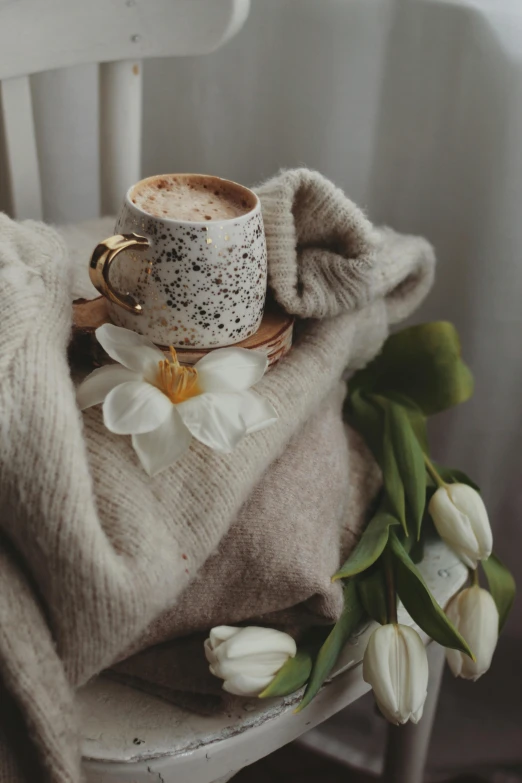 a cup of coffee sitting on top of a wooden chair, a still life, by Anna Boch, trending on pexels, romanticism, magnolias, covered with blanket, brown sweater, gif