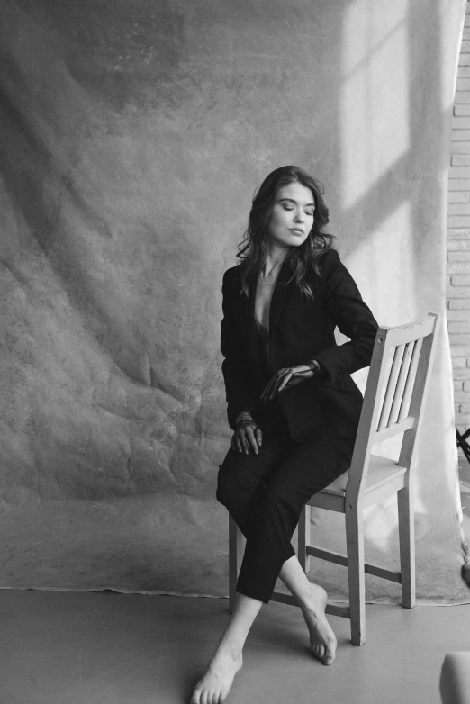 a black and white photo of a woman sitting on a chair, by Niyazi Selimoglu, song hye - kyo, wearing black suit, medium format. soft light, promotional image