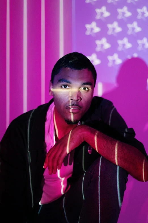 a man standing in front of a purple wall, an album cover, inspired by David LaChapelle, glowing magenta laser eyes, donald glover, bisexual lighting, 2010s