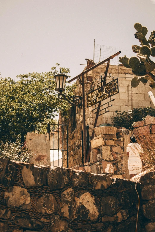 a man riding a skateboard on top of a stone wall, a colorized photo, by Daniel Lieske, trending on unsplash, renaissance, entrance to 1900's mine, signboards, cyprus, dilapidated house