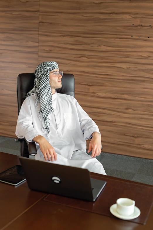 a man sitting in a chair in front of a laptop, inspired by Sheikh Hamdullah, pexels contest winner, dau-al-set, office clothes, arab inspired, ( ( theatrical ) ), office furniture