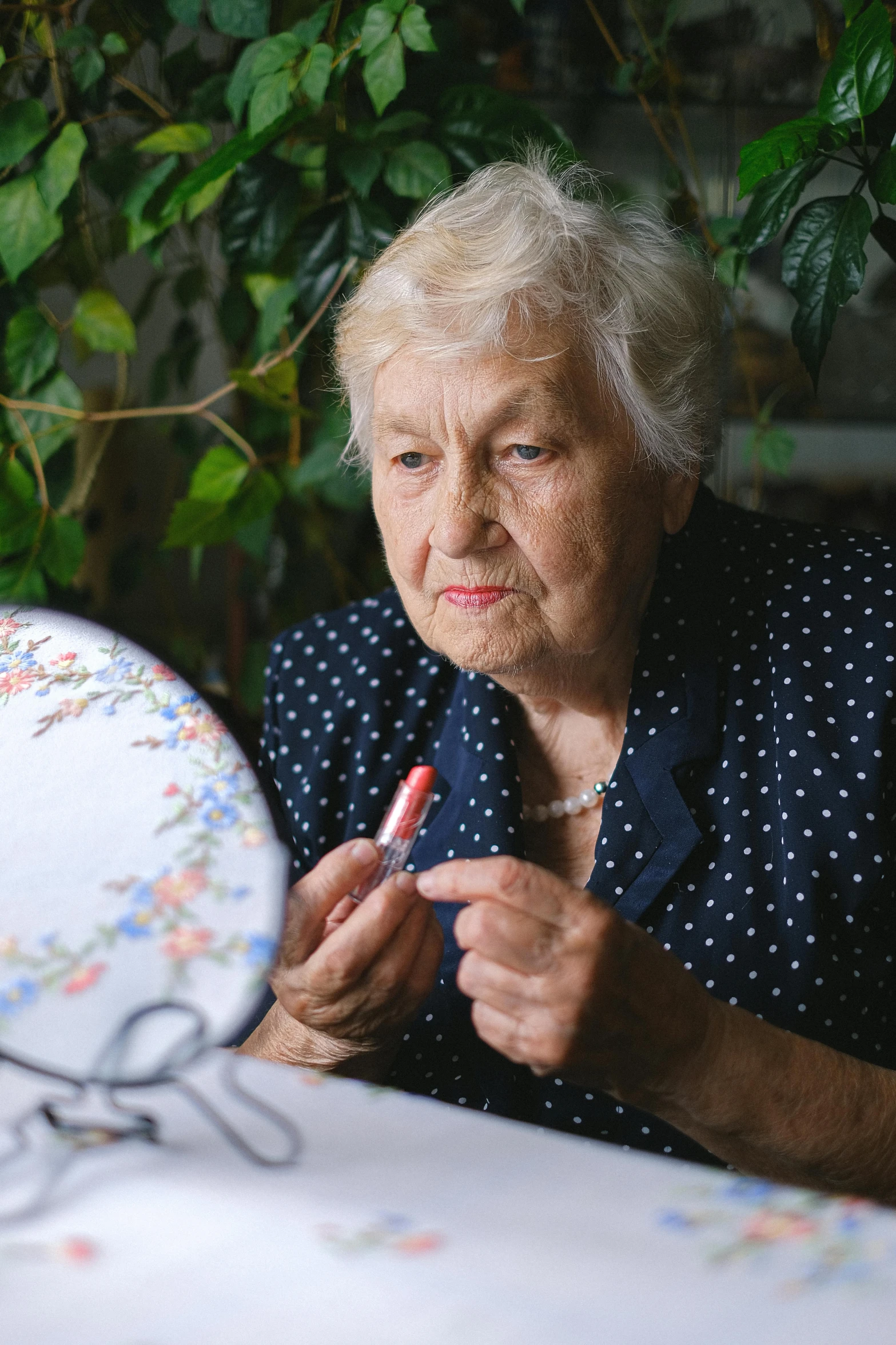 a woman sitting at a table with a plate in front of her, a cross stitch, inspired by Margareta Sterian, pexels contest winner, putting on lipgloss, looking old, expert artist, high quality image