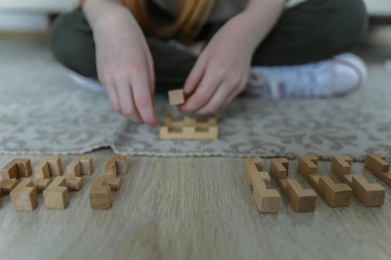 a girl playing with wooden blocks on the floor, a jigsaw puzzle, inspired by Isamu Noguchi, unsplash, runic words, medium close up portrait, square shapes, voxelart