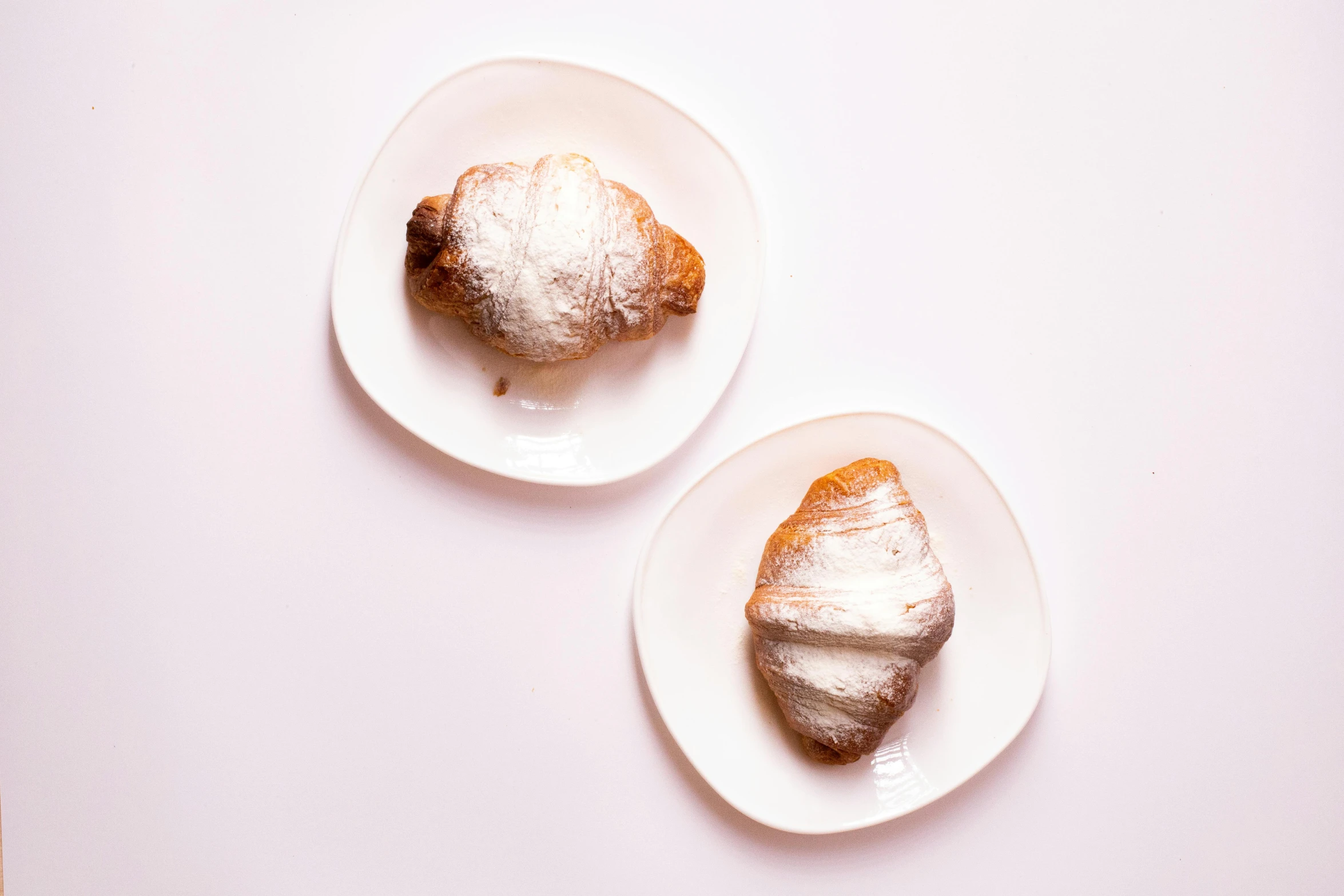 two plates of pastries with powdered sugar on them, inspired by Károly Patkó, unsplash, with a white background, italian, high quality product image”, curved body