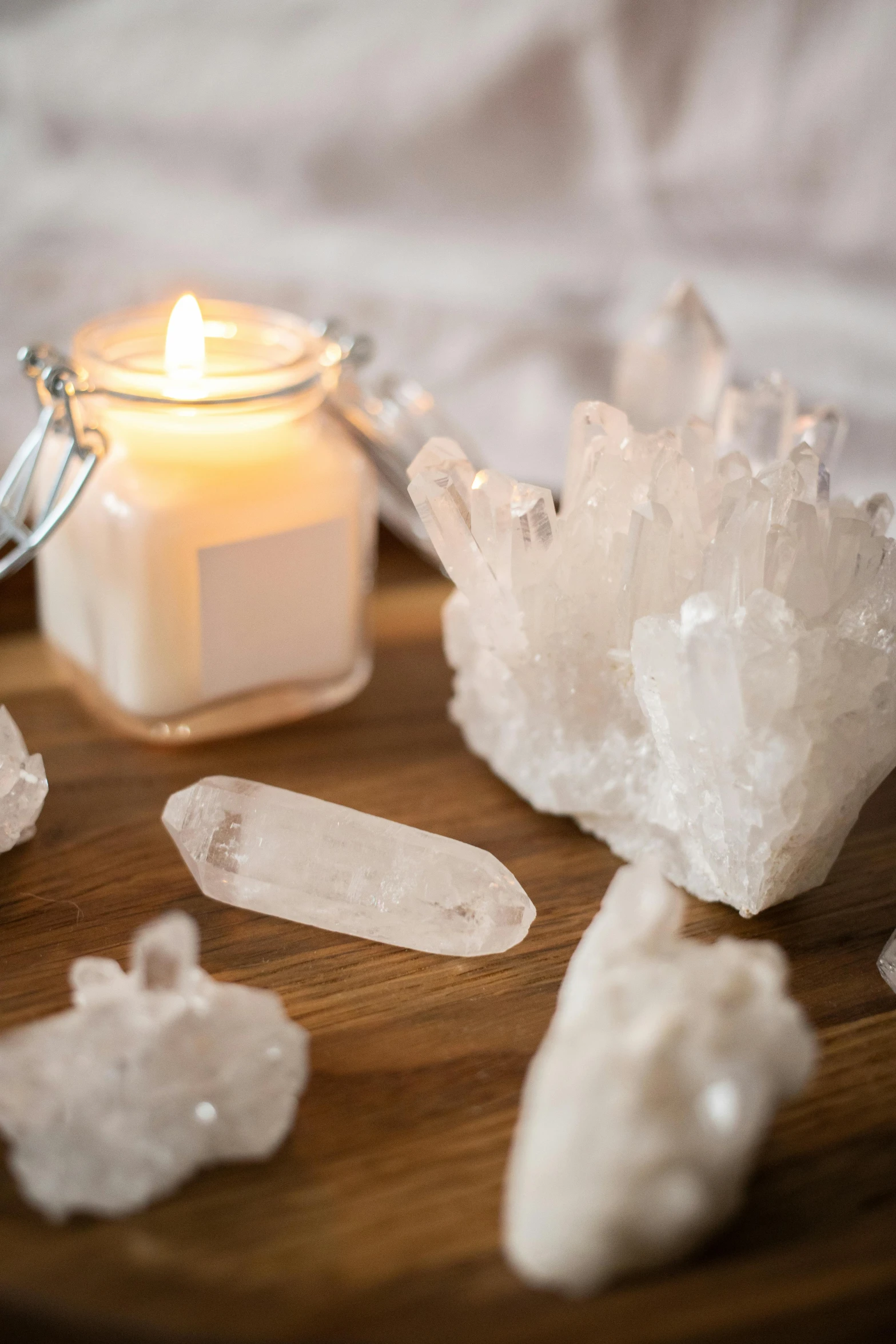 a candle sitting on top of a wooden table next to crystals, trending on pexels, quartz, white, on a wooden tray, lumi