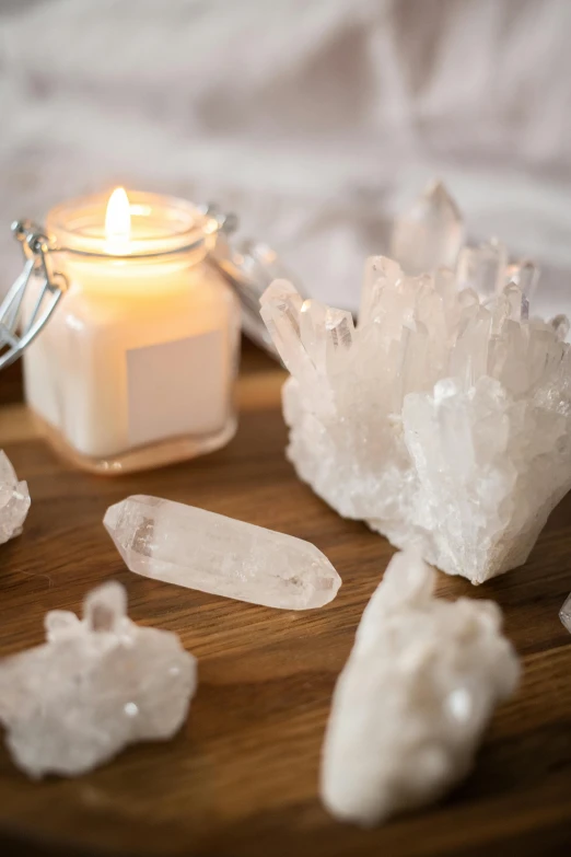 a candle sitting on top of a wooden table next to crystals, trending on pexels, quartz, white, on a wooden tray, lumi