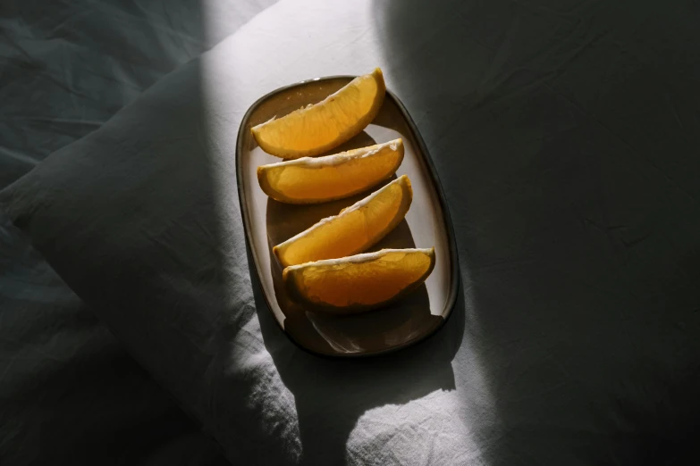 a plate of sliced oranges sitting on a bed, inspired by Tang Di, unsplash, back lit, made of glazed, curved, orange shoulder pads