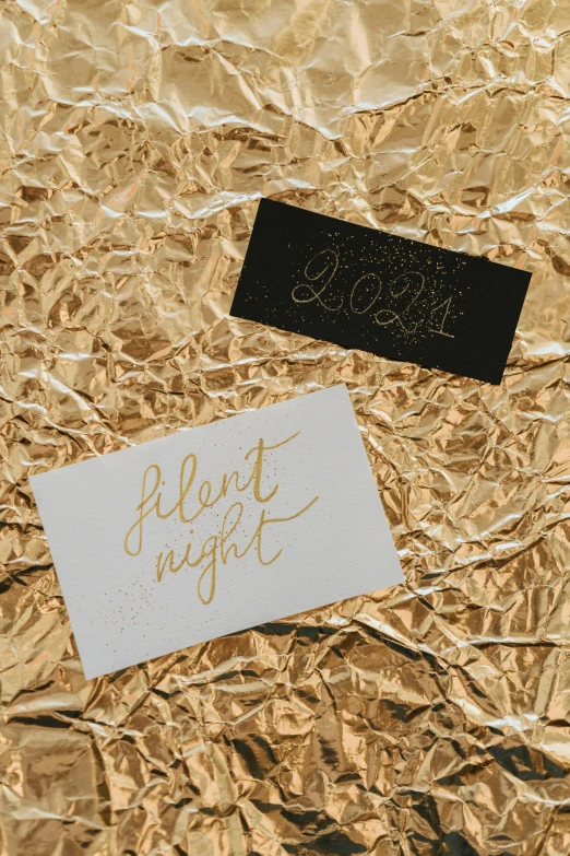 a piece of foil sitting on top of a table, an album cover, by Jessie Algie, unsplash contest winner, under the silent night sky, gold embroidery, business card, detail shots