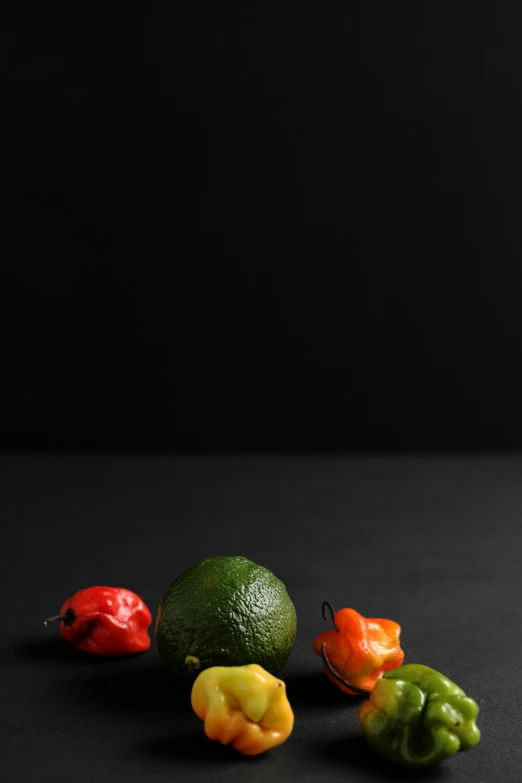 a group of peppers sitting on top of a table, a still life, unsplash, photorealism, black backdrop, avocado, high quality photo, high resolution image