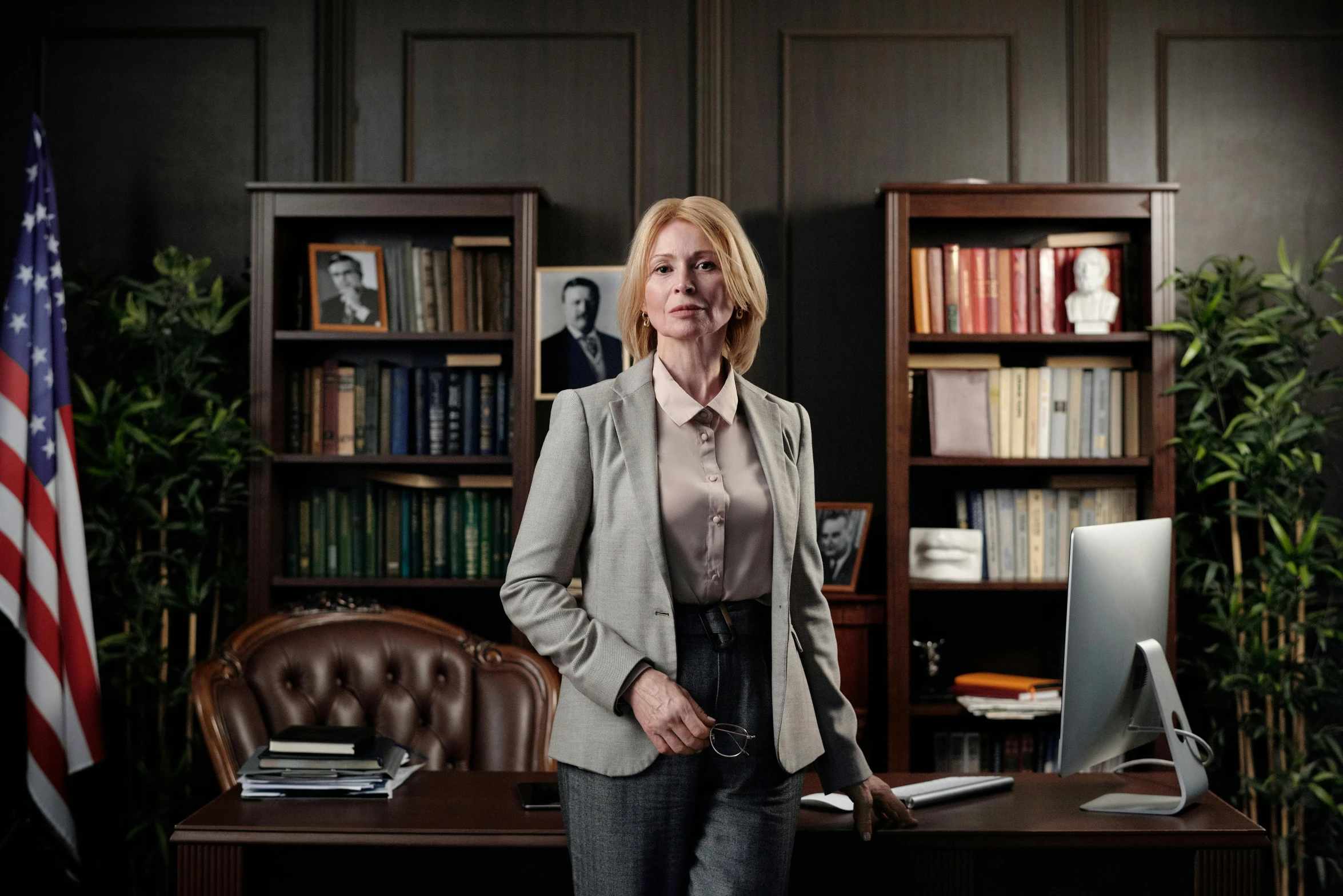 a woman standing in front of a desk in an office, a portrait, pexels, hyperrealism, still image from tv series, president of belorussia, dramatic intense lighting, liz truss