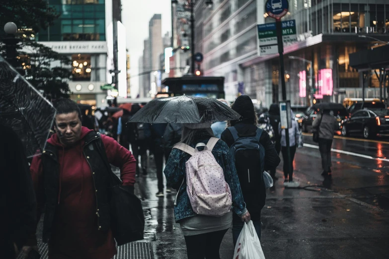 a group of people walking down a street holding umbrellas, a photo, pexels contest winner, post-apocalyptic times square, background image, girl in raincoat, with a backpack