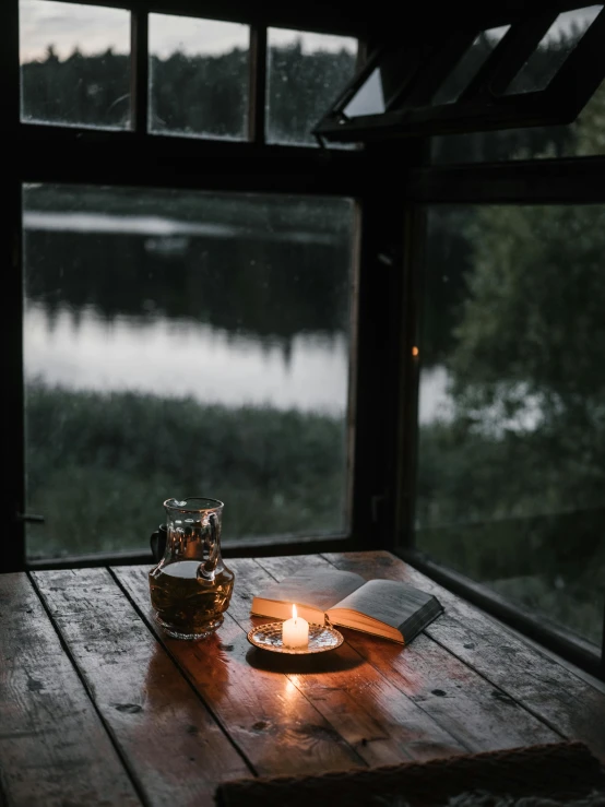 a candle sitting on top of a wooden table, inspired by Elsa Bleda, open window at night, rainy afternoon, lake view, 2019 trending photo