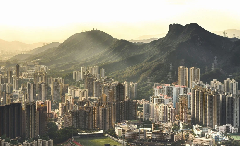 a view of a city with mountains in the background, pexels contest winner, hyperrealism, hong kong buildings, golden hour light, hills, hyperrealism”