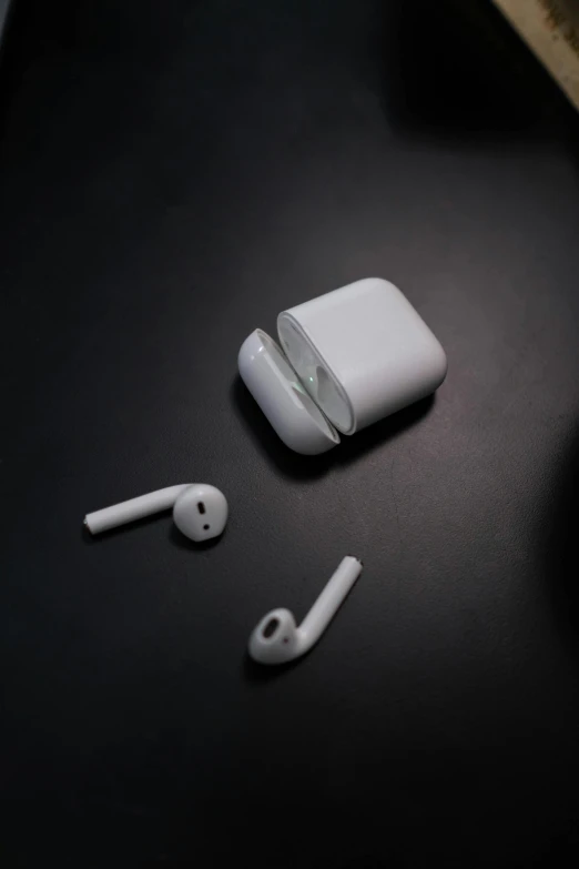 a pair of airpods sitting on top of a table, pexels, on a black background, pipe, set against a white background, earring