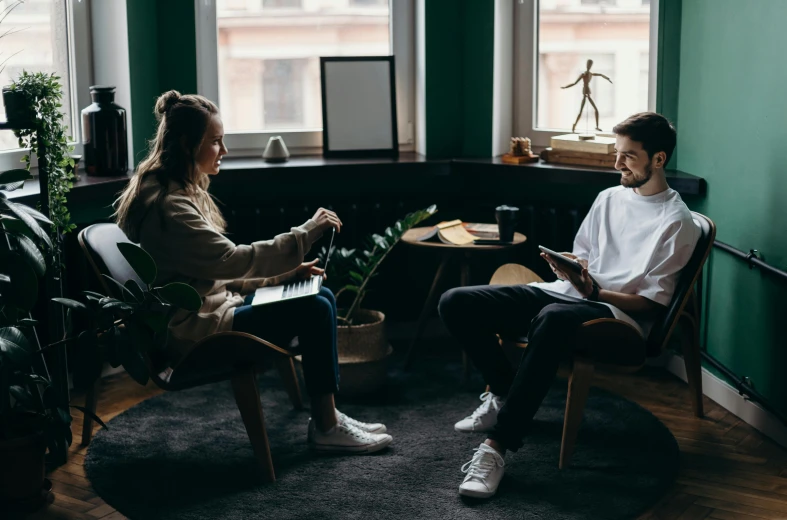 a man and a woman sitting in chairs in a room, cosy vibes, profile image, mental health, on a coffee table