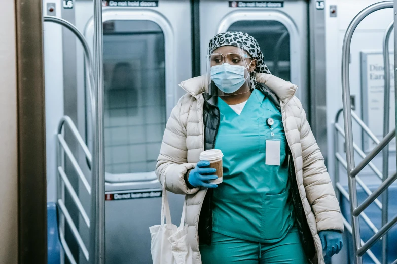 a woman wearing a mask and holding a cup of coffee, by Meredith Dillman, pexels contest winner, nurse costume, in a subway, avatar image, hbo