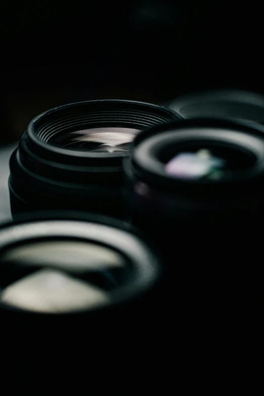 a group of camera lenses sitting on top of a table, a picture, pexels contest winner, photorealism, close-up 35mm macro shot, low-key, looking into camera, full frame image