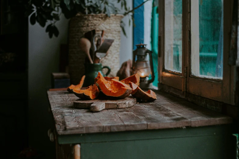 a cutting board sitting on top of a wooden table, a still life, by Elsa Bleda, pexels contest winner, glowing pumpkins under a tree, copper and emerald, windowsill, mushroom